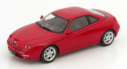 Red 1:18 scale diecast model car, sports coupe with detailed rims and black windows, on white background.