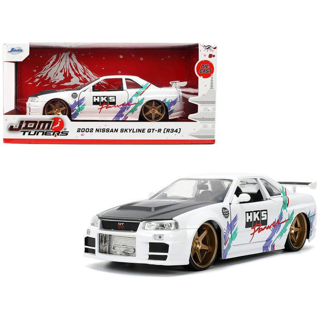 https://cdn.shopify.com/s/files/1/0504/9925/6496/files/2002-nissan-skyline-gt-r-r34-rhd-right-hand-drive-hks-power-white-with-carbon-hood-and-graphics-jdm-tuners-series-124-diecast-model-car-by-jada-364004.jpg?v=1748403644