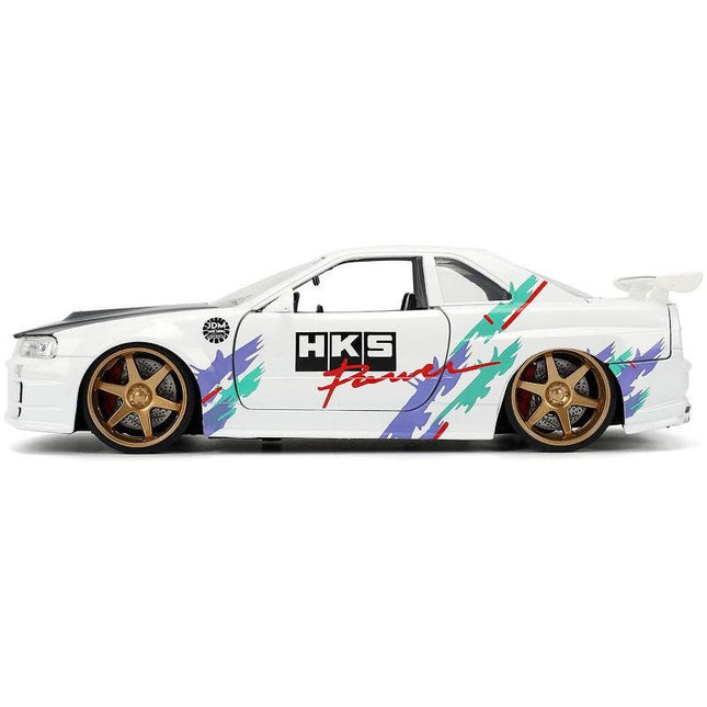 https://cdn.shopify.com/s/files/1/0504/9925/6496/files/2002-nissan-skyline-gt-r-r34-rhd-right-hand-drive-hks-power-white-with-carbon-hood-and-graphics-jdm-tuners-series-124-diecast-model-car-by-jada-622459.jpg?v=1748403644