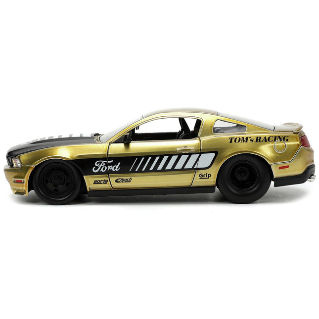 https://cdn.shopify.com/s/files/1/0504/9925/6496/files/2010-ford-mustang-gt-gold-metallic-with-black-graphics-and-hood-toms-racing-bigtime-muscle-series-124-diecast-model-car-by-jada-342946.jpg?v=1748419129