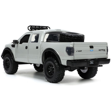 https://cdn.shopify.com/s/files/1/0504/9925/6496/files/2011-ford-f-150-svt-raptor-pickup-truck-light-gray-with-extra-wheels-just-trucks-series-124-diecast-model-car-by-jada-580869.jpg?v=1748403837