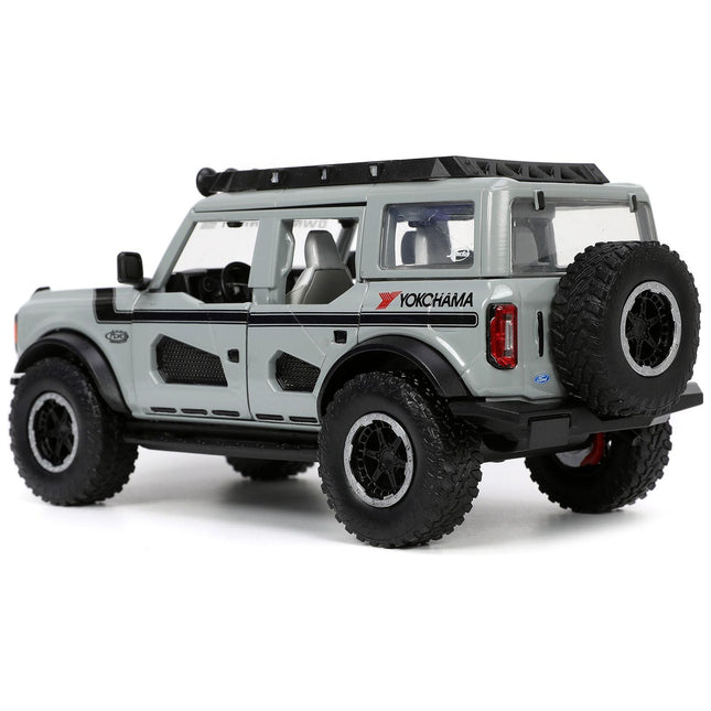 https://cdn.shopify.com/s/files/1/0504/9925/6496/files/2021-ford-bronco-gray-with-black-stripes-with-roof-rack-own-the-night-just-trucks-series-124-diecast-model-car-by-jada-744876.jpg?v=1748419128
