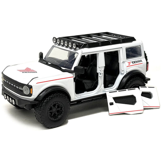 https://cdn.shopify.com/s/files/1/0504/9925/6496/files/2021-ford-bronco-white-with-red-stripes-and-roof-rack-yokohama-tires-just-trucks-series-124-diecast-model-car-by-jada-862269.jpg?v=1748419131