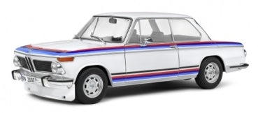 1:18 scale diecast BMW model car in white with blue and red stripes, side view