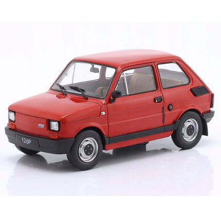 Front-left angled view of a 1:24 scale Fiat 126p diecast model car from 1985, painted in vibrant red, displaying the boxy two-door hatchback body, black plastic bumpers, round headlights, chrome wheel covers, and clear windows revealing a simple interior.