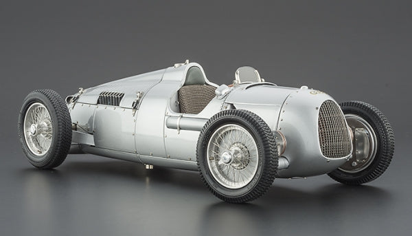 Silver vintage 1:18 scale diecast race car model with wire wheels on a gray background