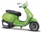 Green diecast model Vespa scooter with black seat on white background