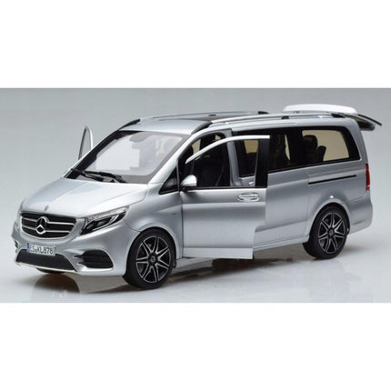 Front-left angled view of a 1:18 scale Mercedes-Benz V-Class (W447) AMG Line 2018 diecast model in brilliant silver metallic with the driver's door and tailgate open, revealing the beige interior and spacious cargo area, and featuring a long van body, chrome grille, black roof rails, and multi-spoke wheels.