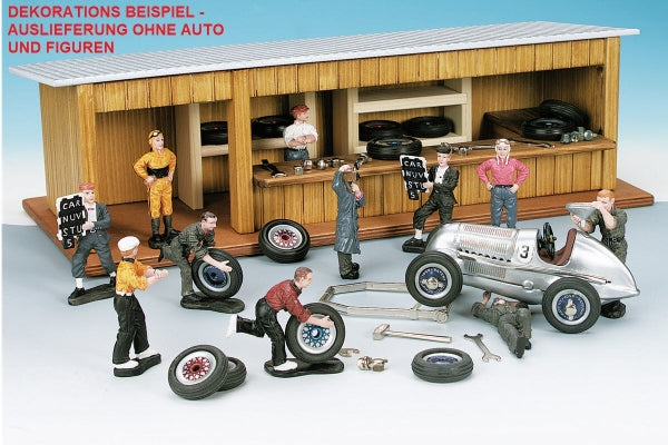 Diecast model car garage diorama with mechanic and driver figurines, tools, and vintage race car