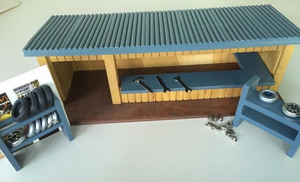 Diecast model car garage diorama with workbench, tools, and model wheels display