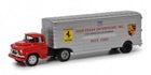 Diecast model of a vintage Ferrari Porsche race car transporter truck, red cab and silver trailer.