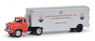 Diecast model of vintage Maserati race car transporter truck with red cab and silver trailer