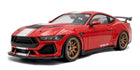 Red diecast model sports car with white stripes and gold wheels, side view