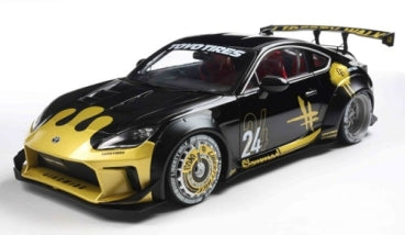 Diecast 1:18 scale Nissan Z race car model, black and gold livery, with rear wing and decals.