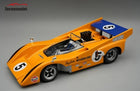 Diecast 1:18 scale orange McLaren Can-Am race car model with blue rear wing and racing decals