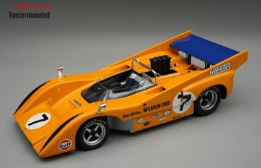 Orange diecast model race car with number 7 and blue rear wing on display