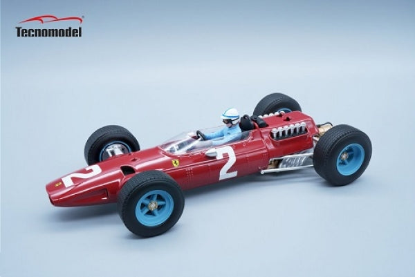 Red diecast Ferrari Formula 1 model car with blue wheels and driver figure on light background