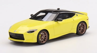 Yellow diecast model sports car with black roof and bronze wheels on white background