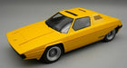 Yellow 1:18 scale diecast model car with angular classic coupe design on grey background