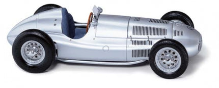 Silver vintage diecast model race car with detailed wheels and blue interior, 1:18 scale.