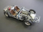 1:18 scale diecast model car chassis with exposed engine, brown seats, and detailed frame